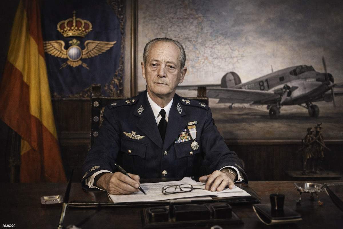 José Rodríguez y Díaz de Lecea, general del Ejército del Aire y ministro, sentado en su despacho oficial con uniforme de aviación, documentos de trabajo y símbolos aeronáuticos al fondo, en una imagen alegórica de su trayectoria militar.