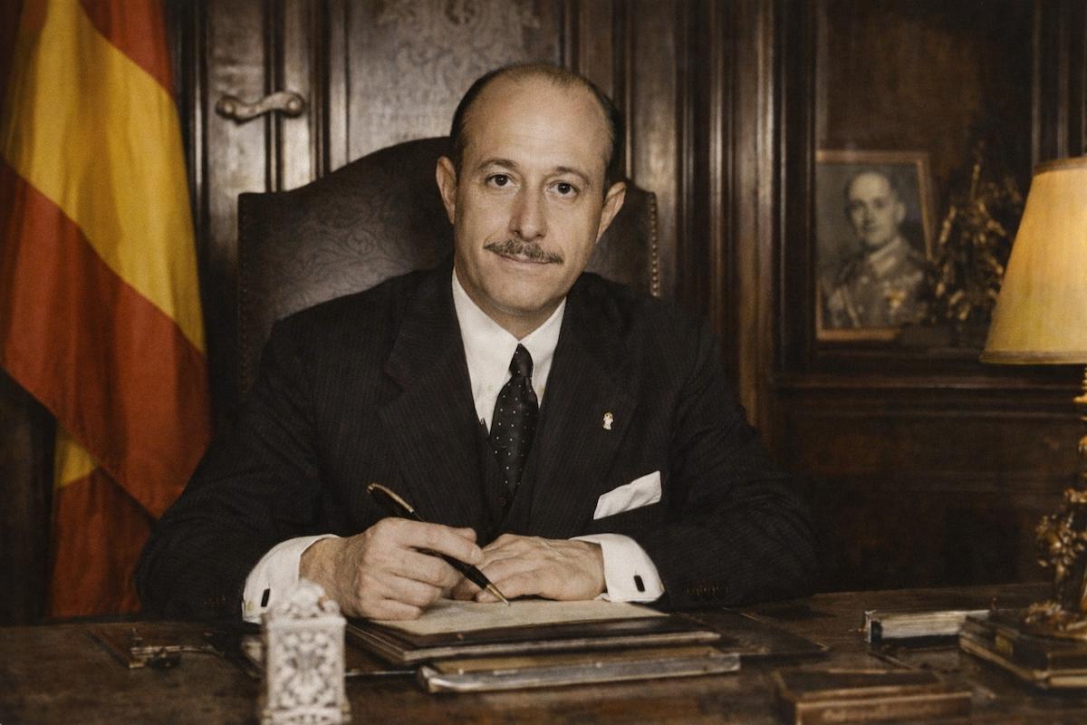 José Finat y Escrivá de Romaní, conde de Mayalde, sentado en su despacho oficial, escribiendo en su mesa de trabajo, con la bandera de España sin escudo al fondo, en una imagen alegórica de su labor política.
