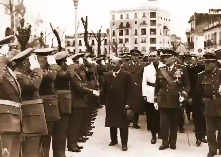 Desfile militar en Córdoba en 1953: autoridades recorren una formación de soldados que saludan, con edificios históricos al fondo.