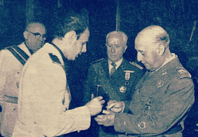 Francisco Franco recibiendo una medalla en un acto oficial, acompañado por varios hombres con uniforme militar y traje, durante una ceremonia institucional en el Ayuntamiento de Berga en 1966.