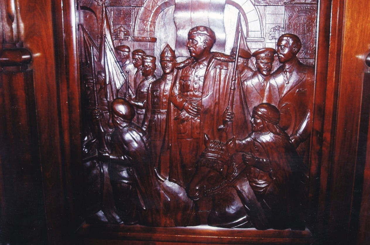Talla en madera sobre dibujo que se hallaba situada en el respaldo de uno de los sillones del salón de sesiones del palacio municipal de La Coruña, y que recordaba la primera visita a La Coruña como jefe de estado de Francisco Franco en 1939. Fue retirada por un equipo de gobierno formado por socialistas y separatistas gallegos en 2007.