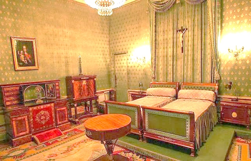 Alcoba matrimonial de SS.EE., tapizada en color verdoso con estampaciones doradas. La cama de la derecha era la de Franco, la de la izquierda la de la Señora. A un lado, debajo de un cuadro de Luis de Morales y junto a un escritorio, el mueble-oratorio que albergó la famosa reliquia de la mano incorrupta de santa Teresa. Ahora está vedada al público. Foto: Patrimonio Nacional.