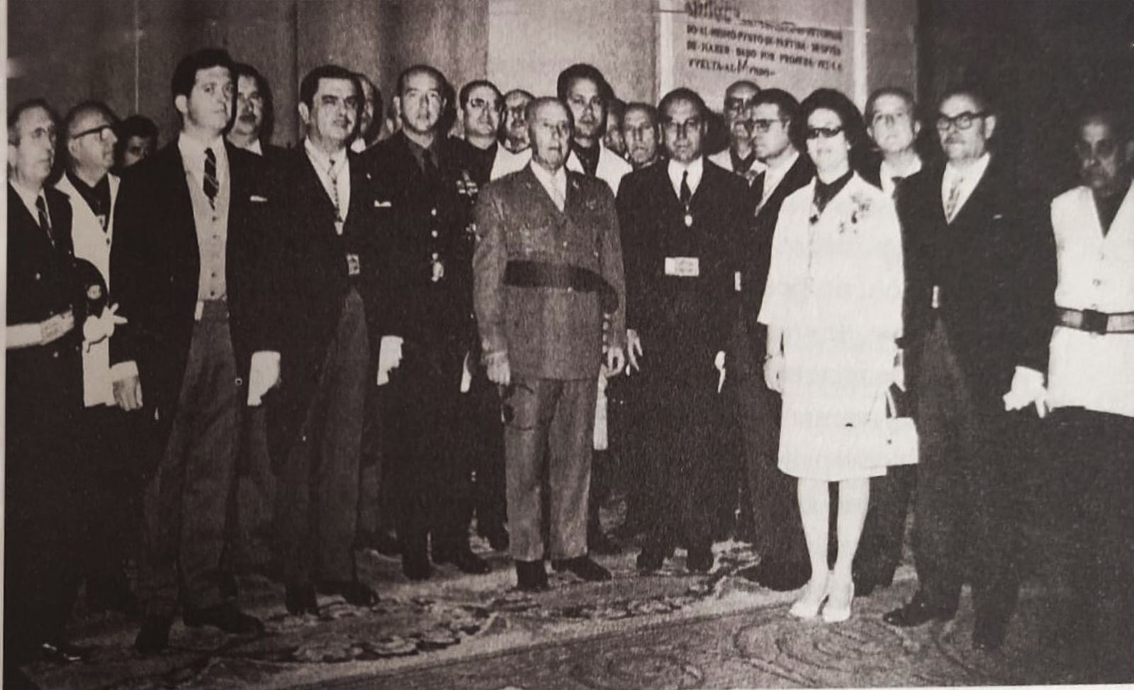 Grupo de autoridades y representantes reunidos en Sevilla en 1963 durante el acto del Consejo Económico Sindical, con Francisco Franco en el centro rodeado de hombres y una mujer en primera fila.