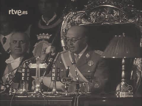 Fotografía histórica aclarada de Franco leyendo un discurso en un acto oficial, sentado en una silla ceremonial y rodeado de micrófonos de Radio Nacional de España y TVE, en un entorno institucional con iluminación mejorada.