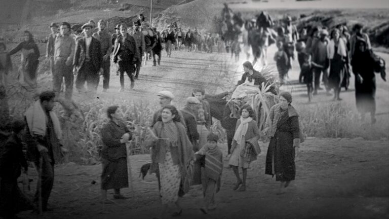 Fotografía histórica en blanco y negro de la Guerra Civil española que muestra a un grupo numeroso de civiles, incluyendo mujeres y niños, caminando por una carretera rural cargando pertenencias, en una escena de huida masiva conocida como la Desbandá entre Málaga y Almería.